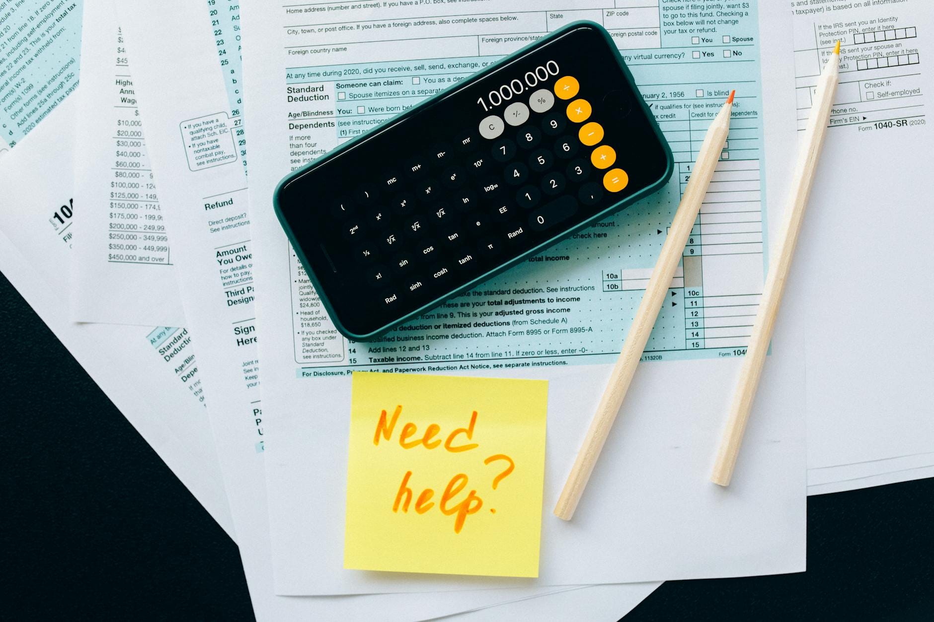 Dokumenty podatkowe z kalkulatorem i notatką z napisem Need help